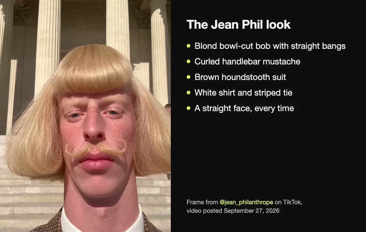 The Jean Phil look on a frame from his TikTok video of September 27, 2026: a blond bowl-cut bob with straight bangs, a curled handlebar mustache, a brown houndstooth suit, a white shirt and a striped tie